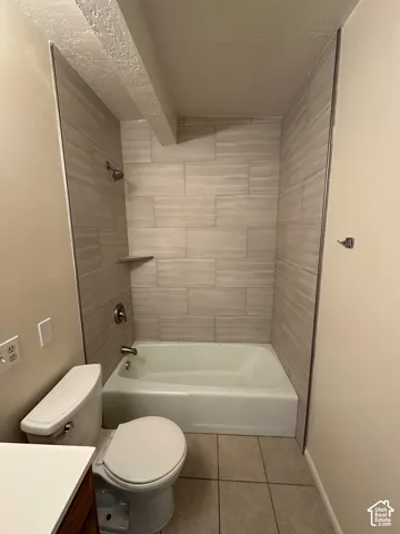 Bathroom featuring a tiled shower surround with a built-in shelf, bathtub, and toilet