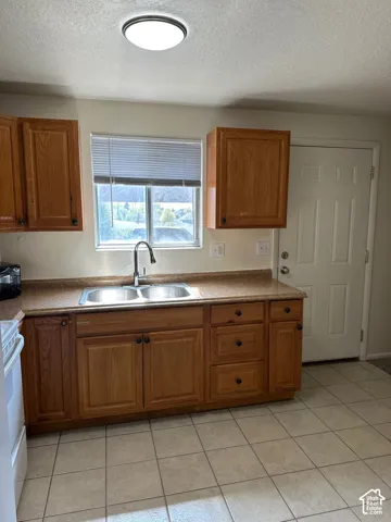 Kitchen featuring wood cabinetry with dark hardware, a dual-basin stainless steel sink, and a window with blinds