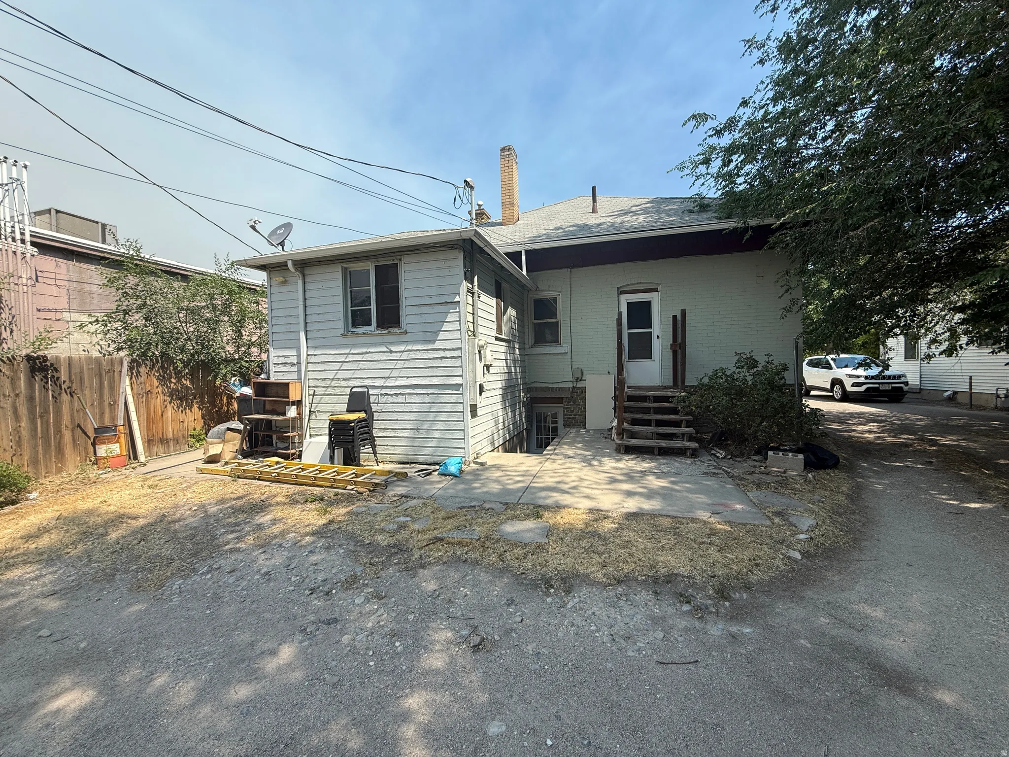 Rear exterior featuring a separate utility structure, an exterior entrance to the main dwelling, and a paved patio area