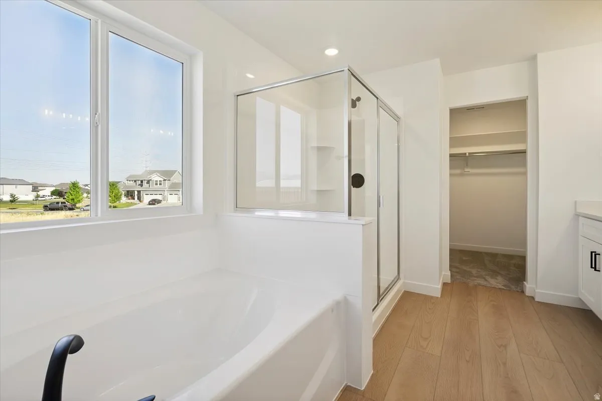 Soaking tub with black fixtures, framed by a large window