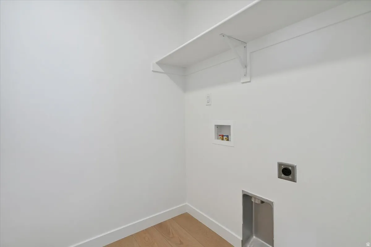 Utility area featuring light wood-finish flooring and crisp white walls
