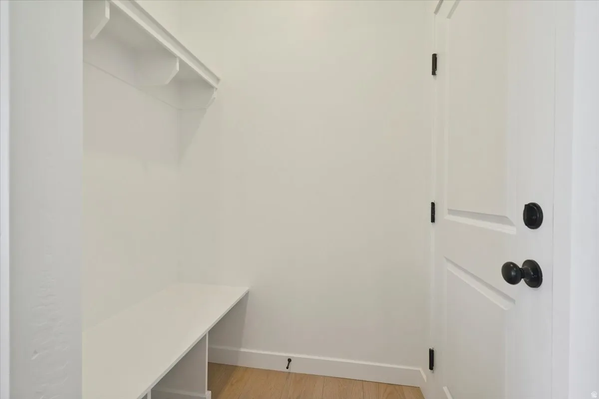 Entryway featuring a built-in bench, overhead shelving, white paneled door, and dark hardware