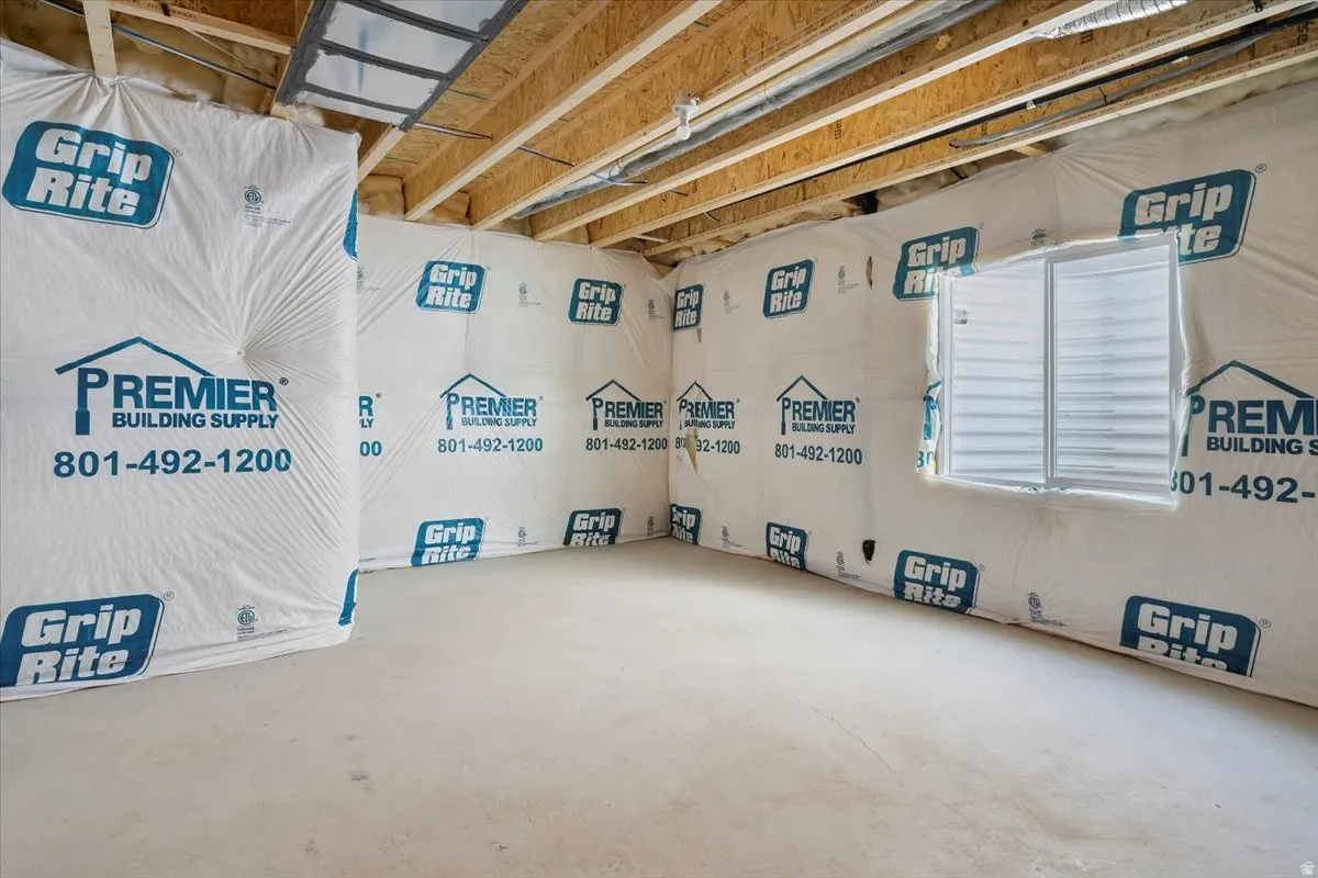 Unfinished basement space with a poured concrete floor and exposed wood ceiling joists