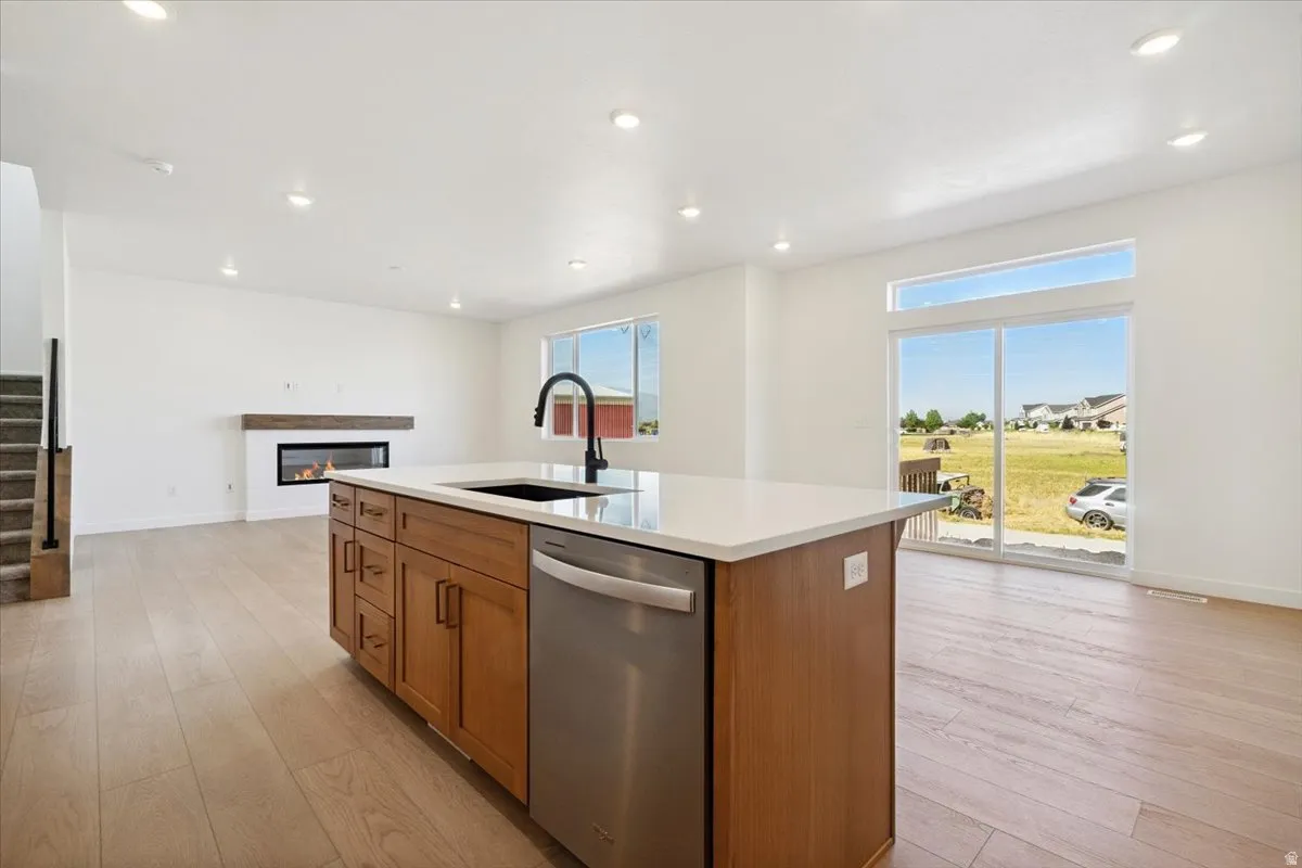 Kitchen island with stone countertop, integrated sink, and stainless steel dishwasher