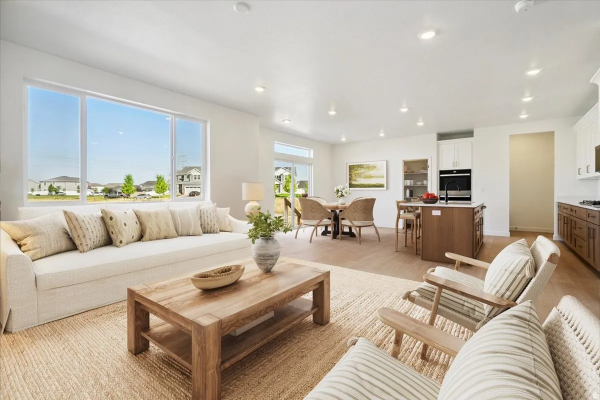 Open-concept living space featuring expansive windows, recessed lighting, wood-finish flooring, a kitchen island with built-in appliances, and white perimeter cabinetry