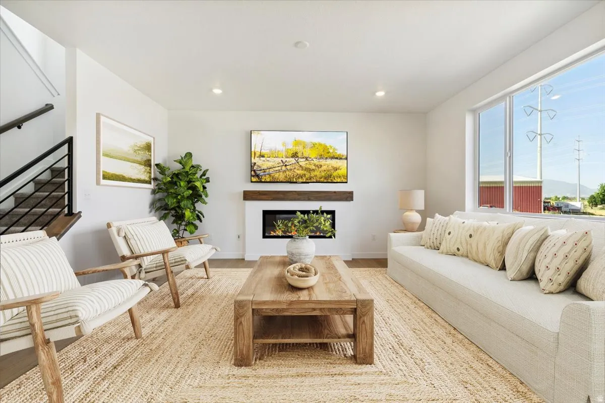 Bright living area featuring wood-finish flooring and a central fireplace with a rustic wood mantel