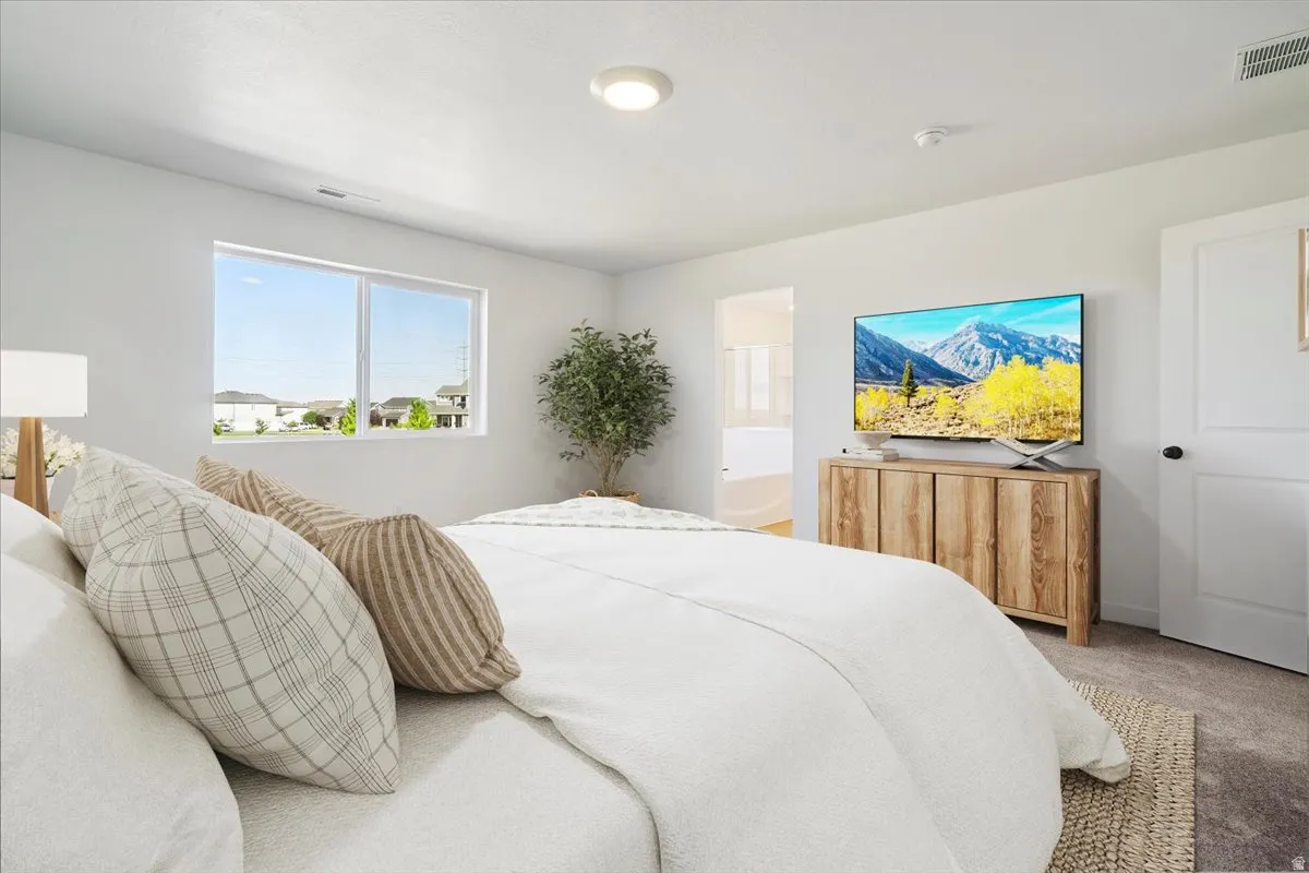 Bright bedroom featuring a large window, neutral carpeting, and a recessed ceiling light