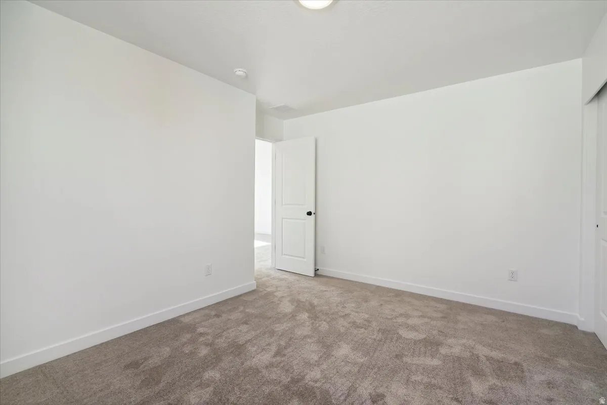 Spacious room featuring neutral carpeting and white painted walls