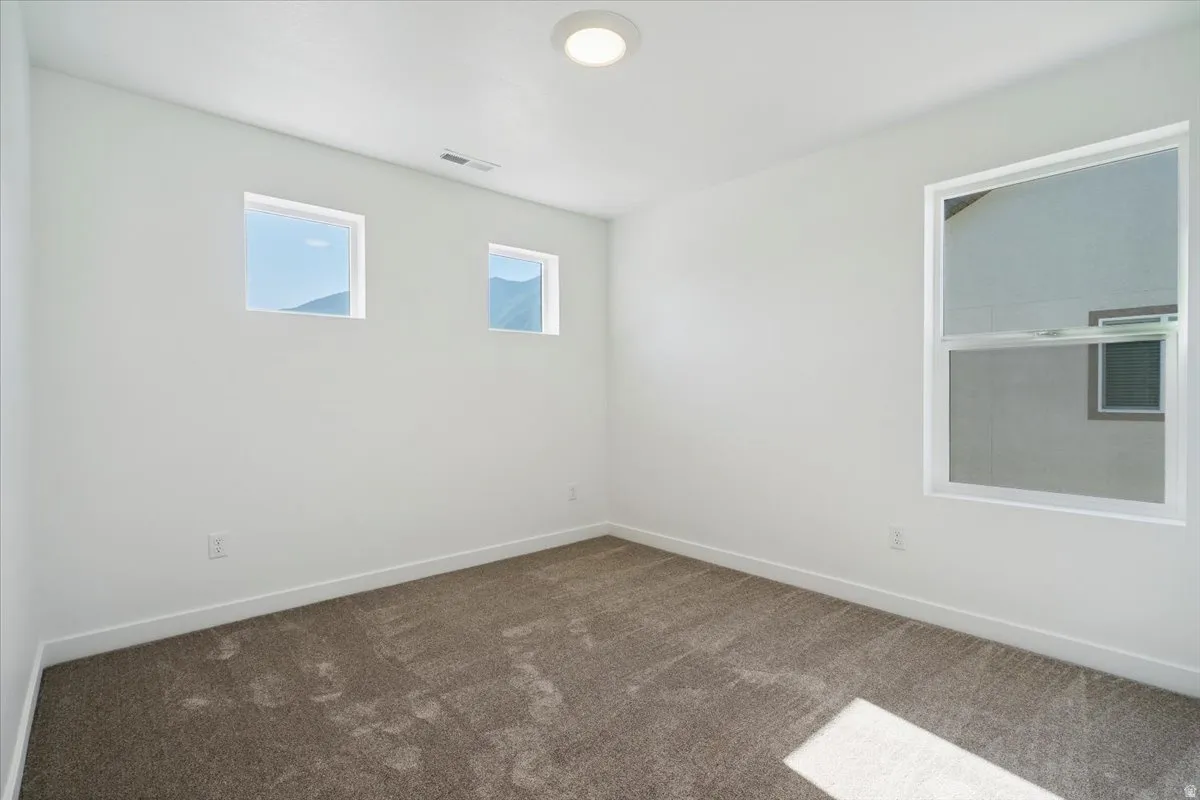 Carpeted interior room featuring white walls and a contemporary flush-mount ceiling light