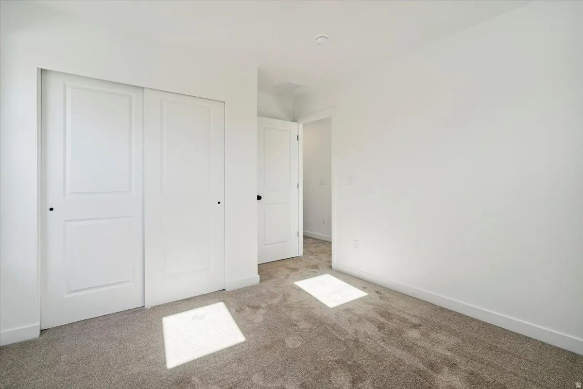 Neutral-toned carpeted flooring with white baseboards and walls