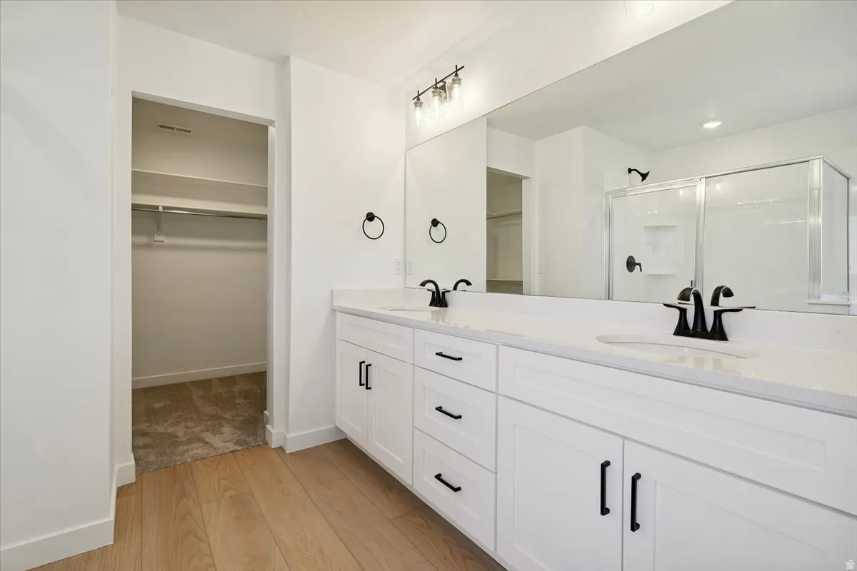 Spacious bathroom featuring a dual vanity with white cabinetry, light-toned countertops, and matte black fixtures