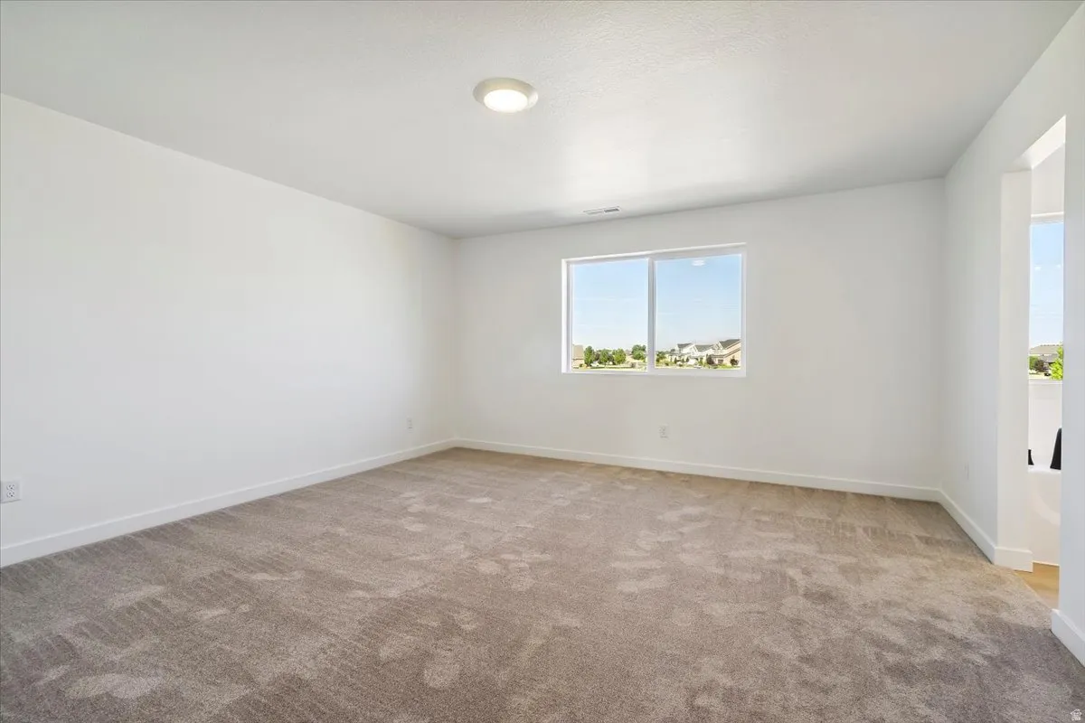 Spacious room featuring neutral carpeting and white wall finishes