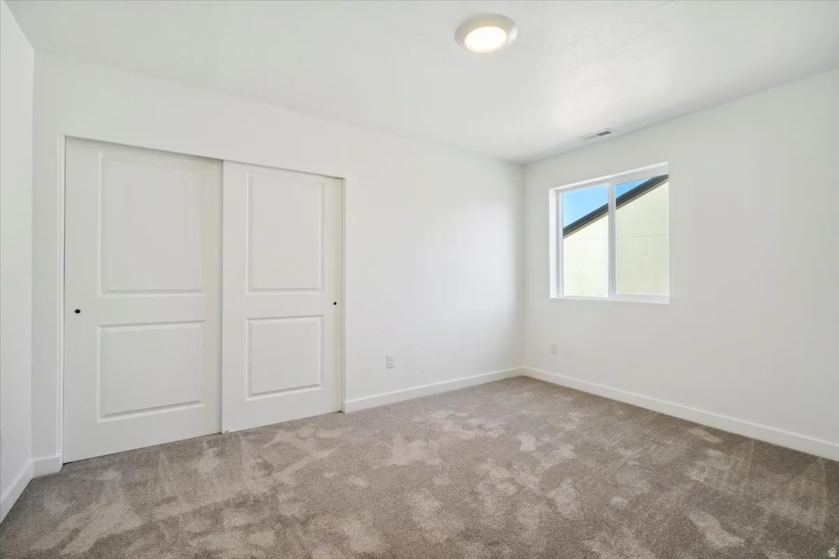 Bright room featuring neutral-toned carpeting, white walls, and a contemporary flush-mount ceiling light