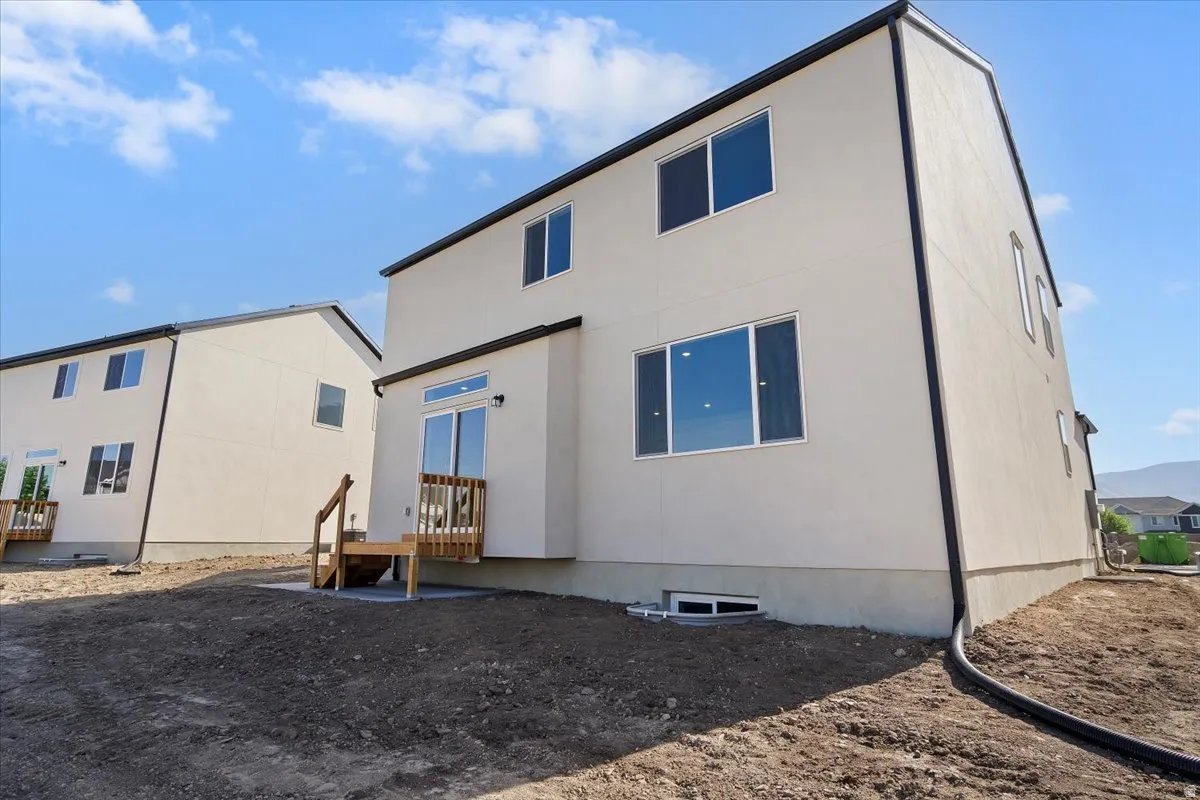 Rear exterior showcasing a wood deck with stairs, a sliding glass door, and multiple windows