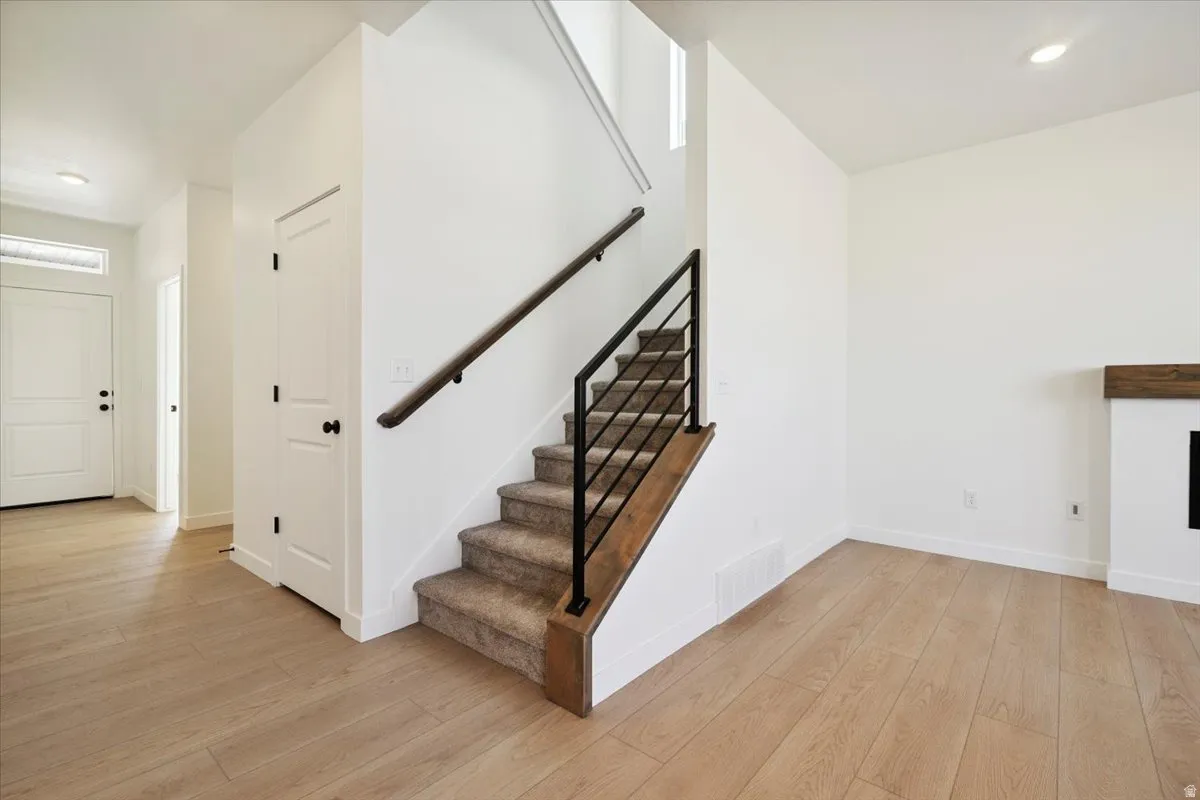 Modern staircase featuring a dark wood handrail, black metal balusters, and carpeted treads