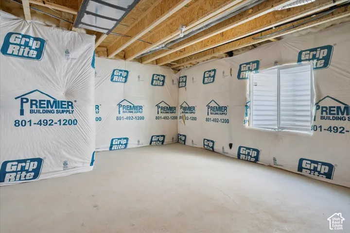 Unfinished basement space with a poured concrete floor and exposed wood ceiling joists