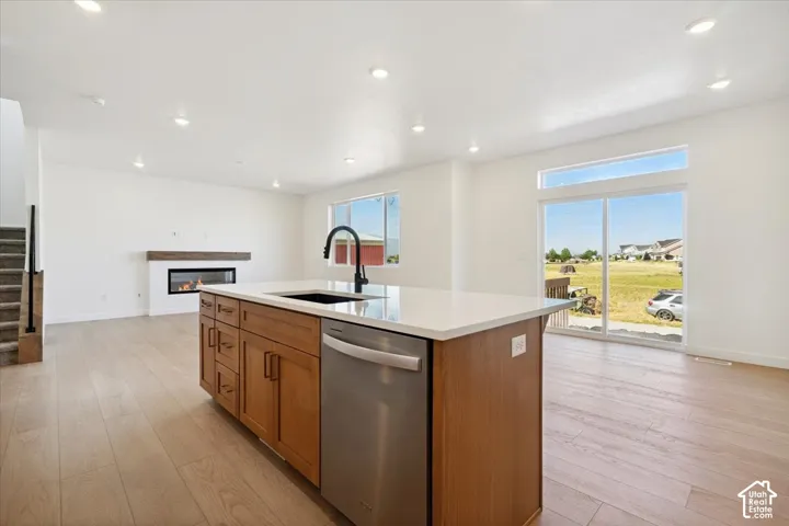 Kitchen island with stone countertop, integrated sink, and stainless steel dishwasher