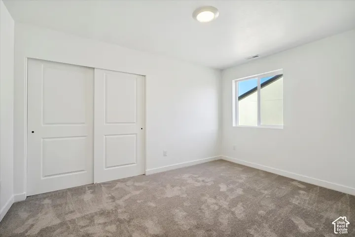 Bright room featuring neutral-toned carpeting, white walls, and a contemporary flush-mount ceiling light
