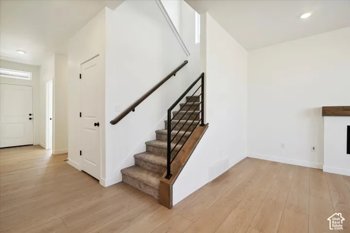 Modern staircase featuring a dark wood handrail, black metal balusters, and carpeted treads