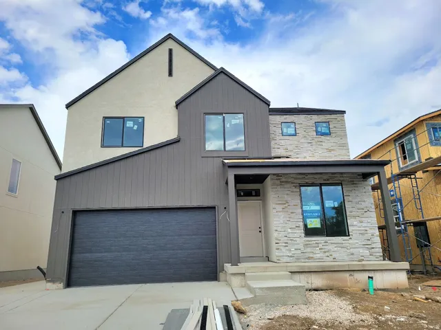 Modern exterior featuring a prominent garage, stone veneer accents, vertical siding, and stucco finishes
