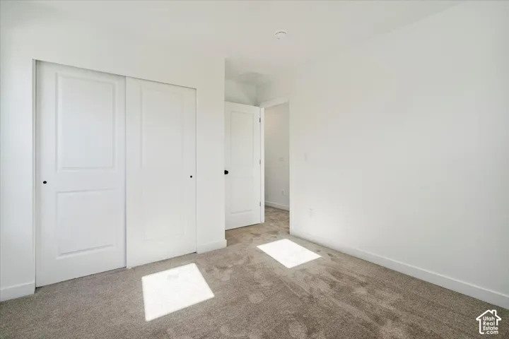 Neutral-toned carpeted flooring with white baseboards and walls