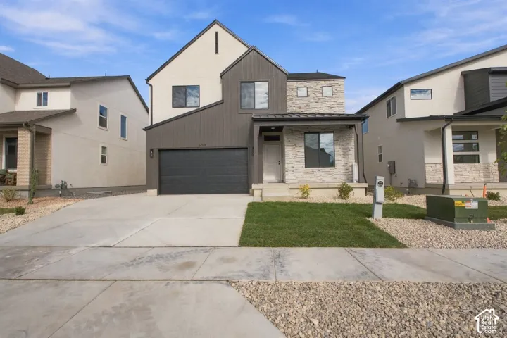 Two-story exterior featuring multi-textured siding, stone veneer accents, a covered front entry, and an attached two-car garage