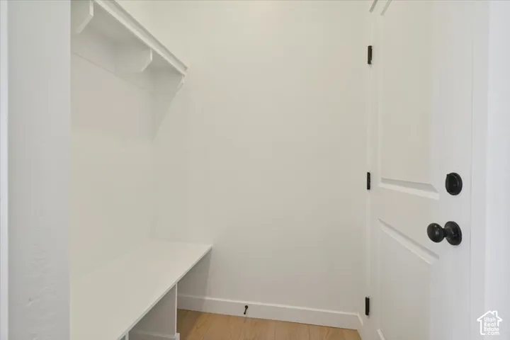 Entryway featuring a built-in bench, overhead shelving, white paneled door, and dark hardware