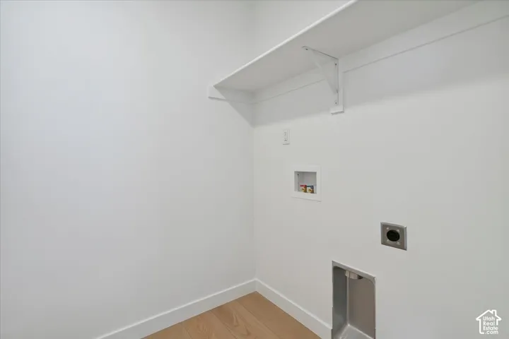 Utility area featuring light wood-finish flooring and crisp white walls