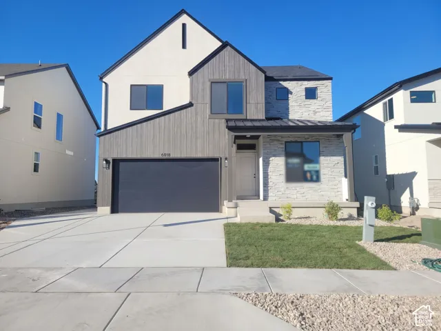 Modern two-story exterior featuring a mix of stucco and vertical wood-grain siding, stacked stone veneer facade, metal roof accents, and a concrete driveway
