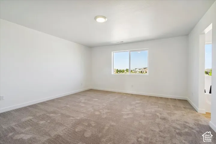 Spacious room featuring neutral carpeting and white wall finishes