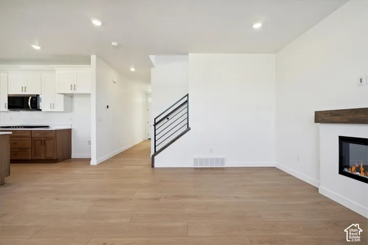 Open-concept living area featuring wood-finish flooring, recessed lighting, and a modern fireplace with a wood mantle