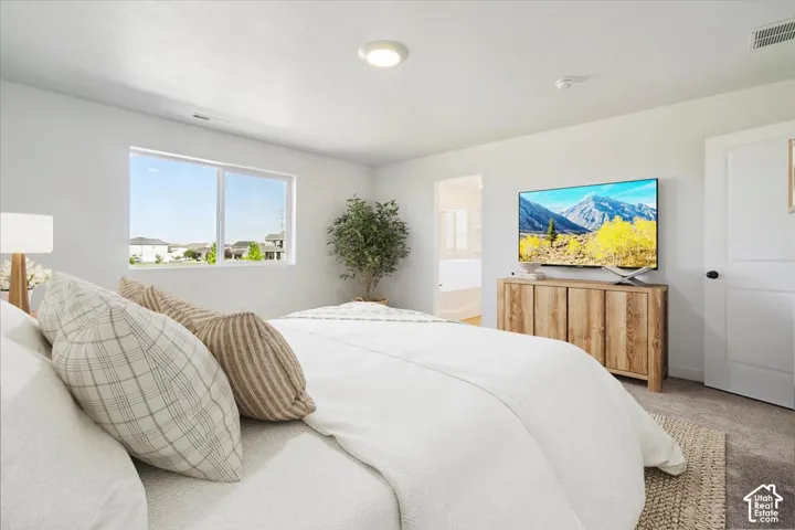Bright bedroom featuring a large window, neutral carpeting, and a recessed ceiling light