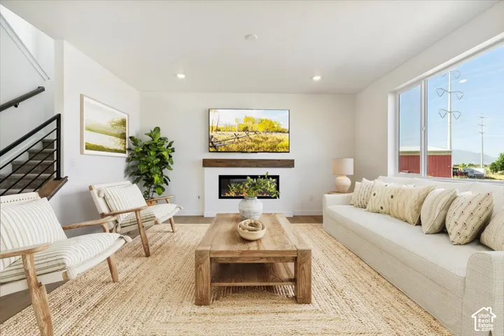 Bright living area featuring wood-finish flooring and a central fireplace with a rustic wood mantel