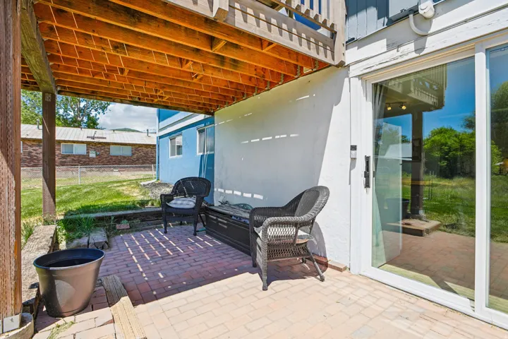 Covered patio featuring brick paver flooring, a white exterior wall, and a sliding glass door