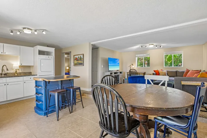 Open-concept living area featuring a kitchen with white cabinetry and granite countertops