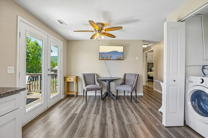 Spacious living area featuring wood-finish flooring, a ceiling fan, and double French doors opening to an exterior deck