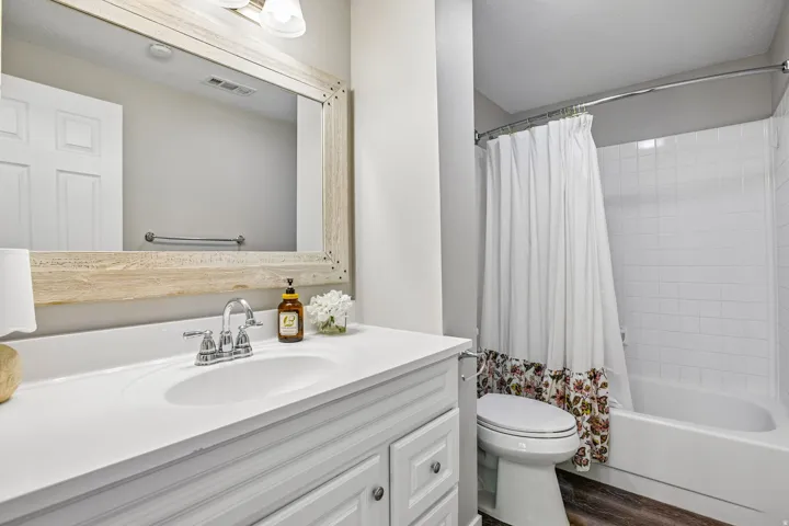 Bathroom featuring a single vanity with an integrated sink, polished chrome faucet, and a large wood-framed mirror