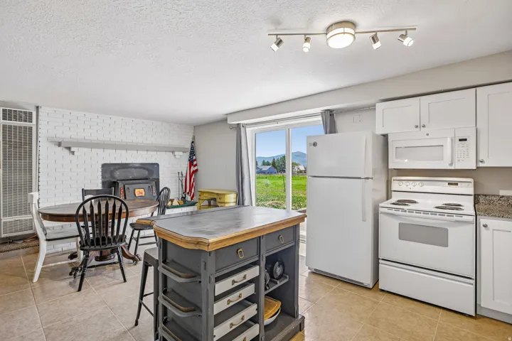 Kitchen featuring a full suite of white appliances, white cabinetry, and granite-patterned countertops