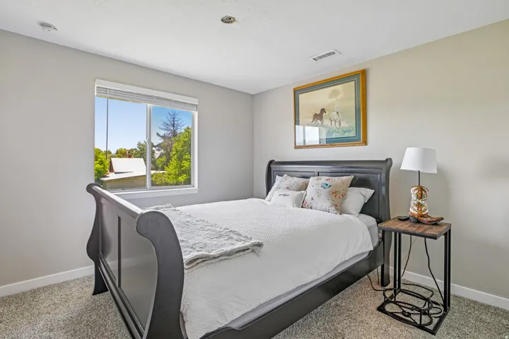 Carpeted bedroom featuring a large window, light gray walls, white baseboards, and a recessed ceiling light