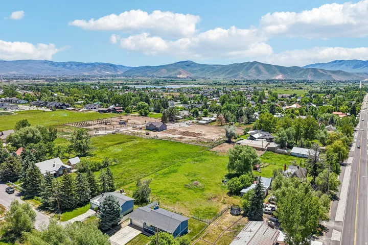 Expansive aerial capturing a wide landscape featuring residential properties, mature trees, and open green fields