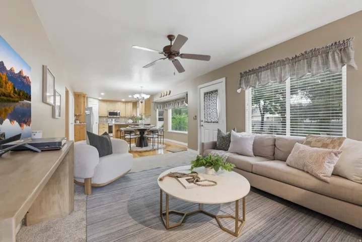 Open-concept living space featuring a ceiling fan, a large window, and light-toned wall paint