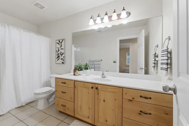 Bathroom featuring a light-toned wood vanity with ample storage, an integrated sink, and a large wall-mounted mirror