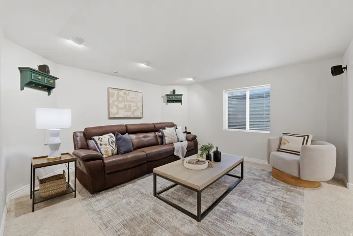 Spacious living area featuring light-colored walls, recessed ceiling lighting, and a window with horizontal blinds
