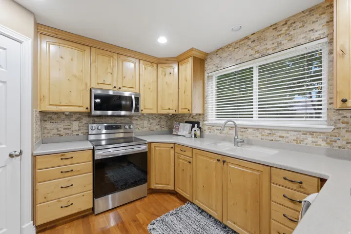 Kitchen featuring light wood cabinetry, light-toned countertops, and a mosaic tile backsplash