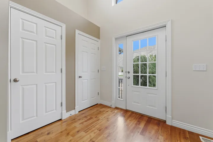 Foyer featuring wood-finish flooring, white paneled doors, and a decorative glass entry door with a sidelight