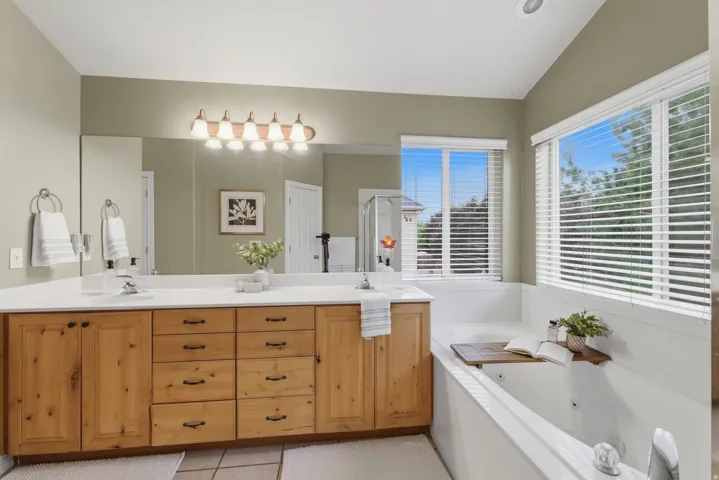 Double vanity with light wood cabinetry, white countertops, and dual undermount sinks