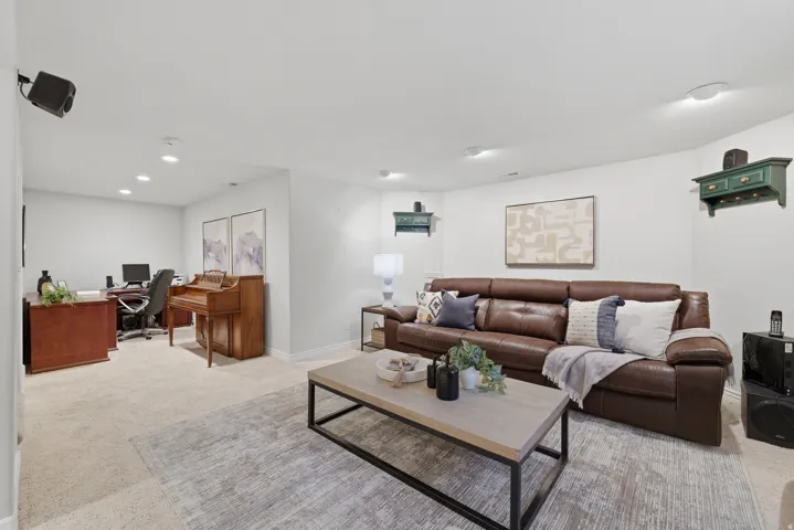 Spacious recreation room featuring recessed lighting, light-toned carpet, and a dedicated office area with built-in cabinetry