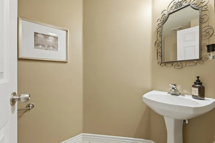 Pedestal sink with chrome-finish faucet and ornate wall-mounted mirror