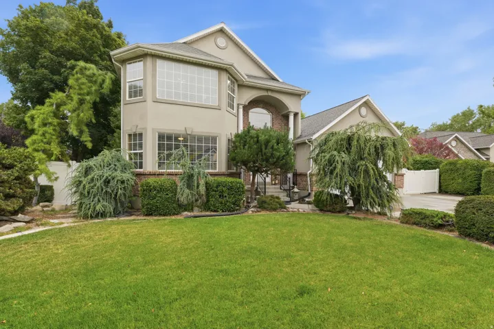 Stucco exterior with brick accents, featuring large bay windows, arched entry, and an attached garage