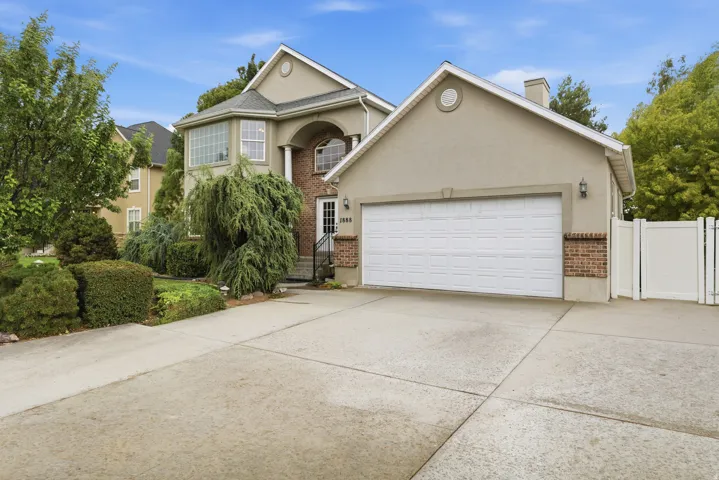 Stucco and brick exterior featuring a two-car garage, concrete driveway, and established front landscaping
